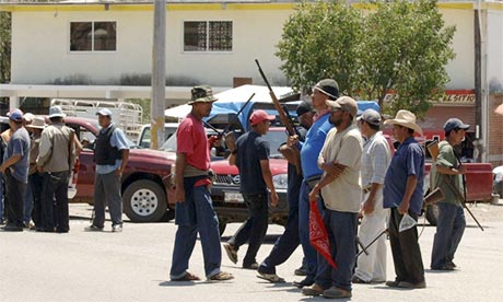 Armed men stand at the entrance to the town of Tierra Colorada, Mexico, where vigilantes have arrested local police and officials accused of gang links. (Photo Credit: Alejandrino Gonzalez/AP)